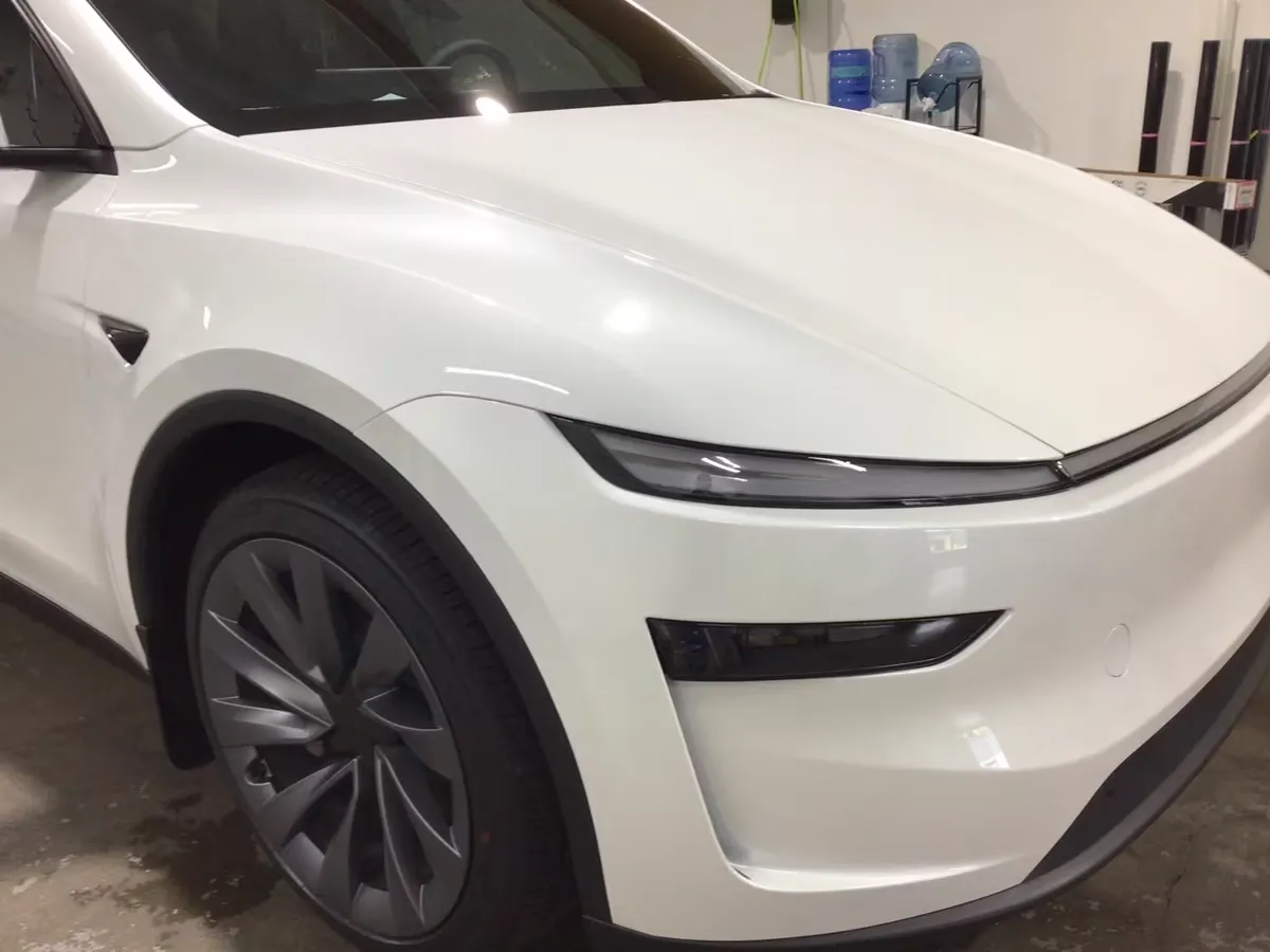 Front corner of a white Tesla Model Y inside the APC shop